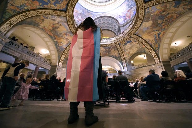 Individual wears a transgender flag as a counter protest during a rally in favor of a ban on gender-affirming health care legislation, March 20, 2023, at the Missouri Statehouse in Jefferson City, Mo.
